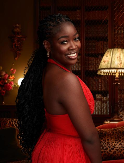Portrait of a smiling Black woman in a red dress.