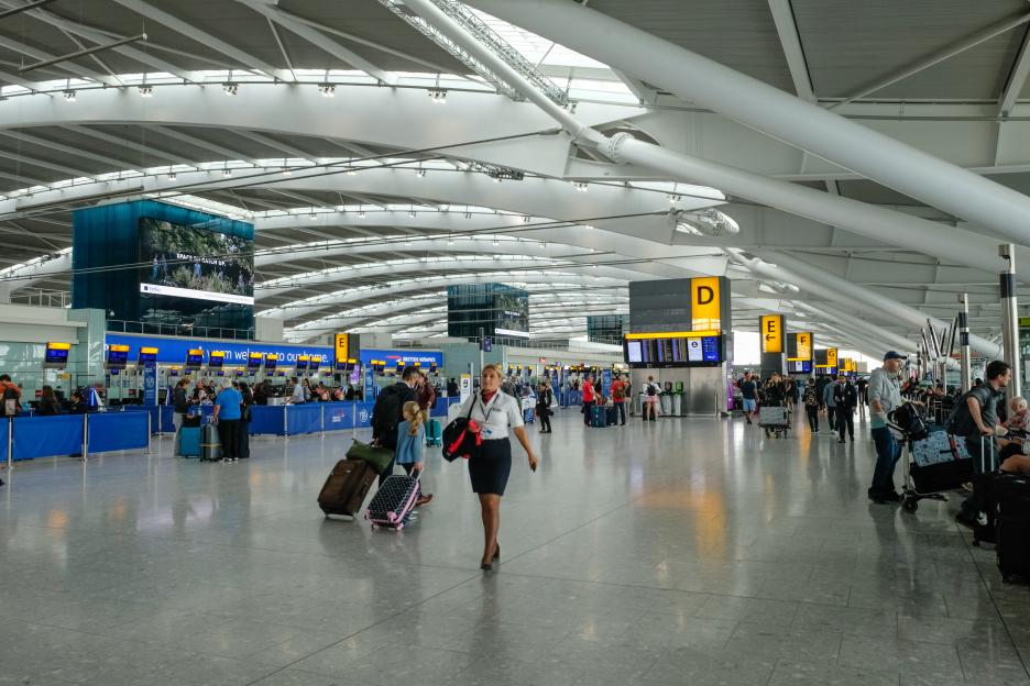 Heathrow Airport terminal with passengers and airline staff.