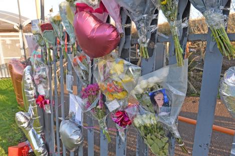 Flowers and balloons left at a fence as a memorial.