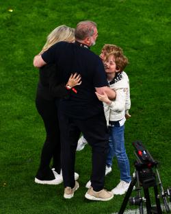 Tottenham Hotspur head coach Ange Postecoglou celebrating with his family on the field.