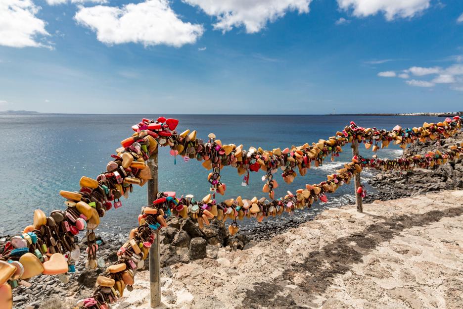 Colorful love locks on a viewpoint overlooking the ocean in Lanzarote, Spain.