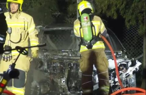 Firefighters at the scene of a burnt-out car.