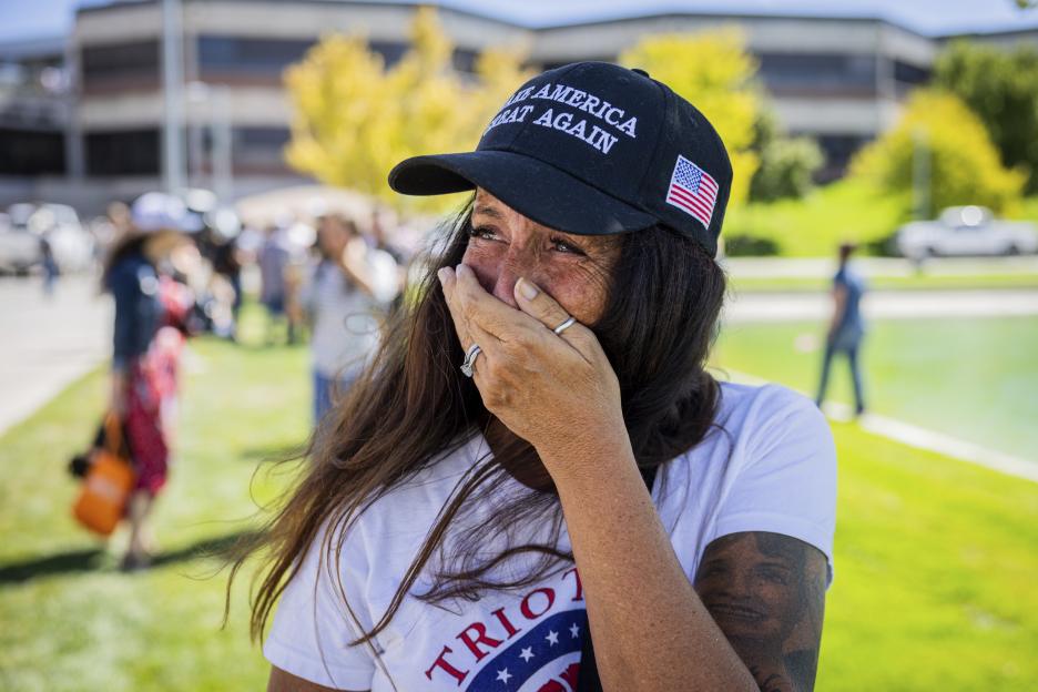 Woman crying, wearing a "Make America Great Again" hat.
