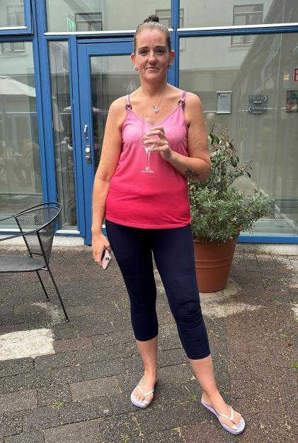 Woman standing outdoors holding a glass of wine.