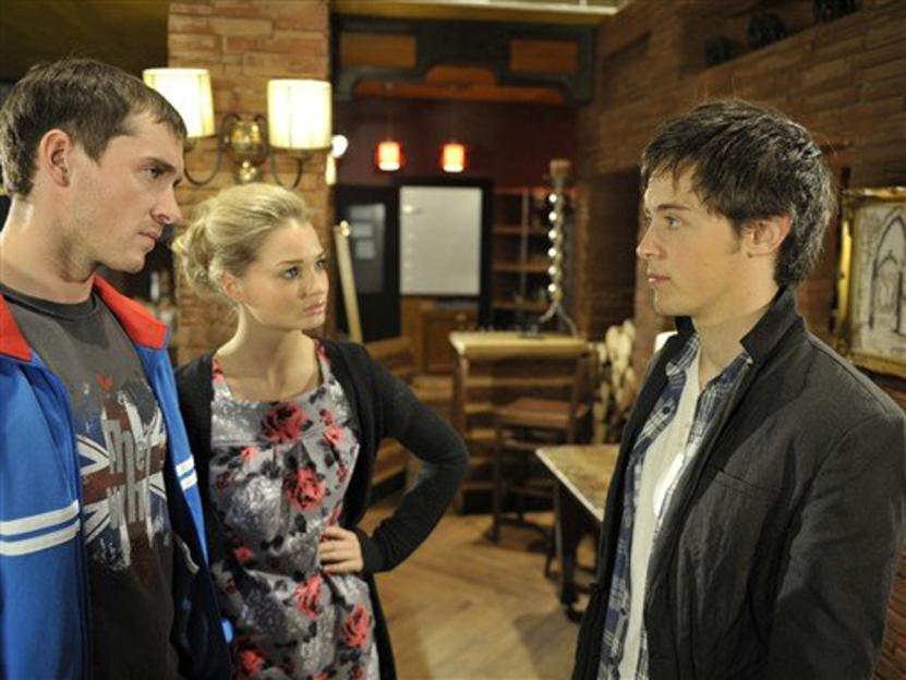 Elliot James Landridge looking at another man while a woman stands between them.