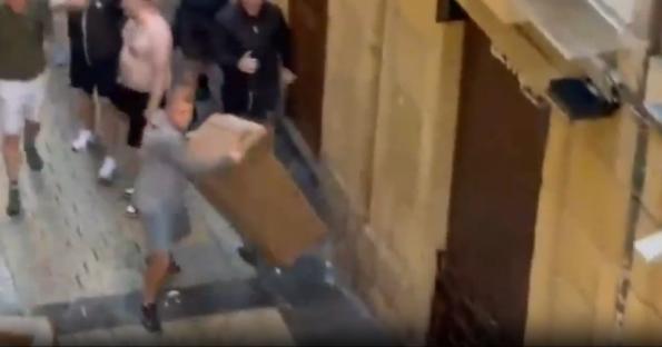 Person carrying a large box while being chased by a group of people.
