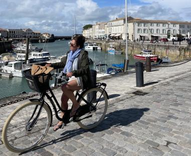 Woman biking by harbor in Il De Re.