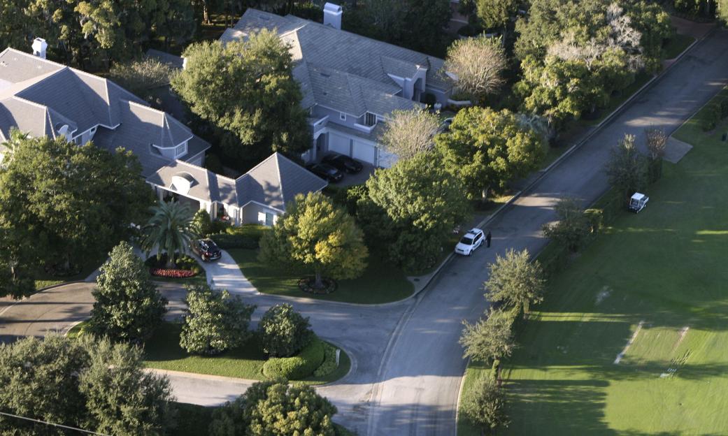 Aerial view of Tiger Woods' house in Windermere, Florida, with a security officer standing by a white vehicle on the street.