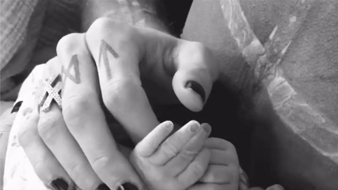 Black and white photo of adult hands holding a baby's hand.