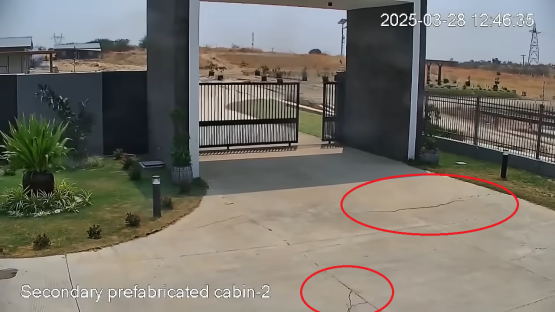 Ground cracks near a building after an earthquake.