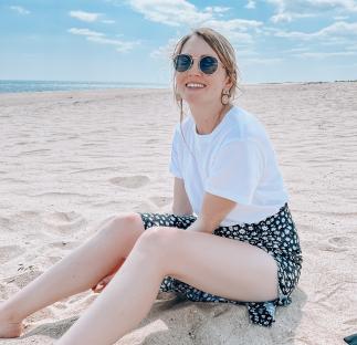 Woman sitting on a sandy beach.