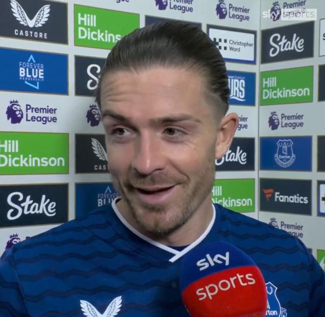 A man with slicked-back hair is being interviewed by Sky Sports, in front of a backdrop featuring various logos including Premier League, Castore, Hill Dickinson, Stake, and Everton.