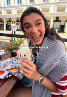 Woman excitedly showing off a Labubu plush toy.
