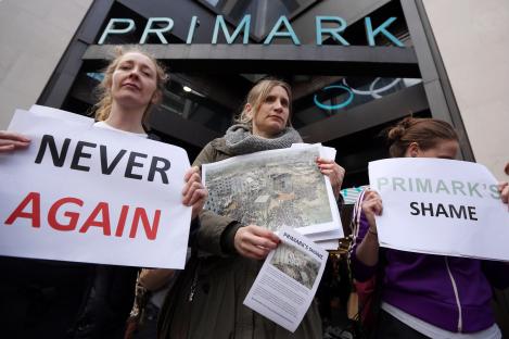 Protestors outside a Primark store holding signs demanding compensation for victims of a clothing factory collapse.