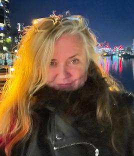 Woman with blonde hair in a black leather jacket at night.