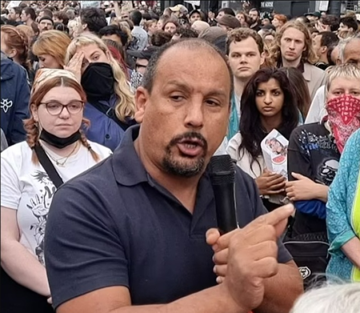 Man speaking into microphone at a protest.