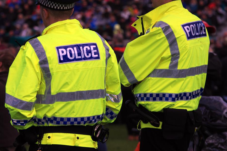 Two UK police officers patrolling at a large crowd venue.
