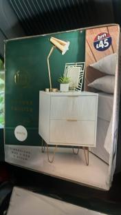 Box showing a white bedside table with gold legs.