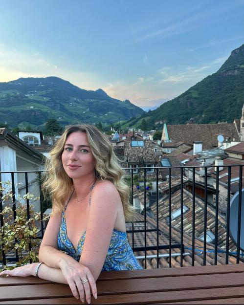 Woman in blue dress on rooftop overlooking Italian town.