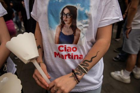 Person holding a candle and wearing a t-shirt with a photo of Martina Carbonaro and the words