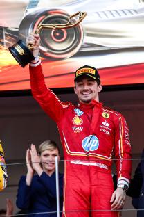 Charles Leclerc holding a Formula 1 Monaco Grand Prix trophy.