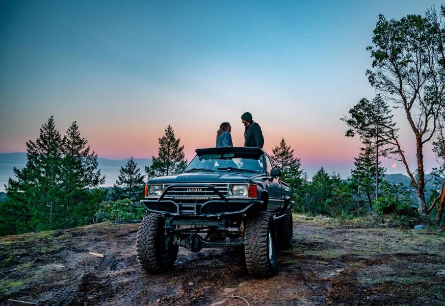 Couple standing on their truck at sunset.