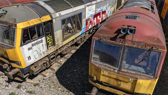 Aerial view of abandoned, rusting diesel locomotives in a quarry.
