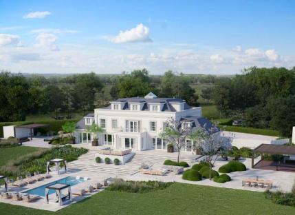 Aerial view of a large white mansion with a pool and landscaping.
