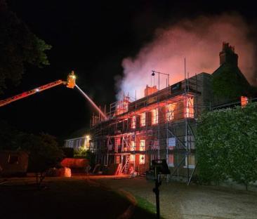 Firefighters battling a house fire at night.