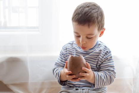 Toddler holding a partially eaten chocolate Easter egg.