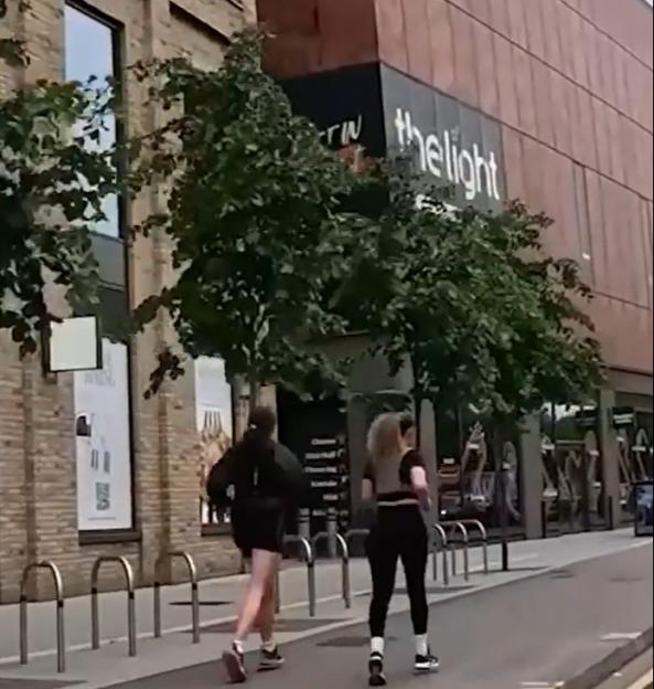 Two people walking past The Light.