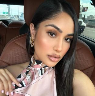 Woman in car wearing pink halter top and gold earrings.