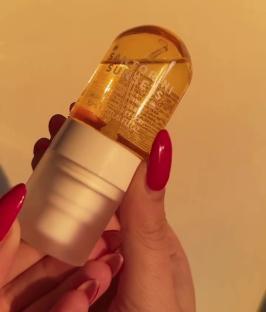 A hand holding a bottle of Primark's Santorini Sunset body oil.