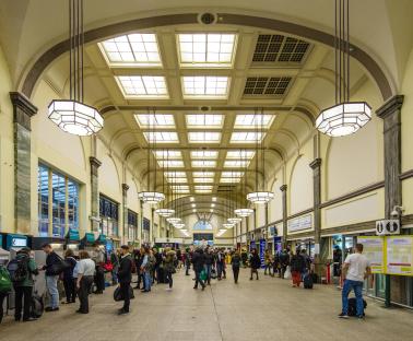Art Deco interior of Cardiff Central railway station with evening commuters.
