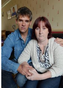 Parents holding hands, grieving the murder of their daughter.