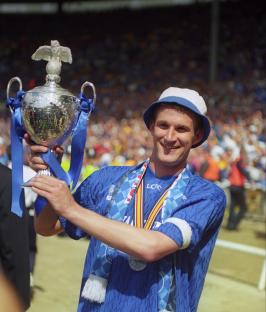 Soccer player holding a trophy at a stadium.