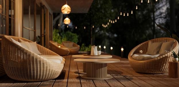 Illustration of a cozy outdoor deck at night with wicker chairs and a coffee table.
