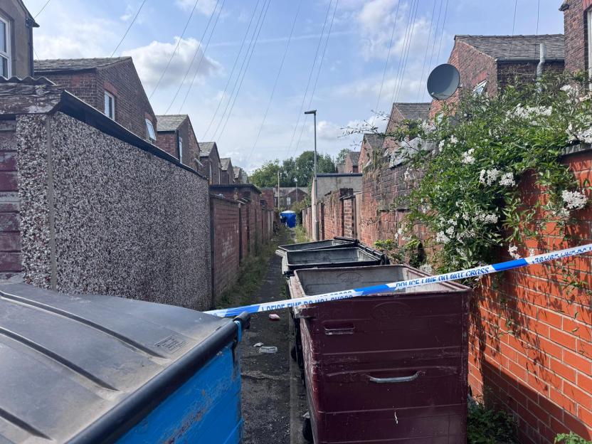 Police tape across an alleyway crime scene.