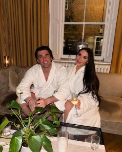 Couple in bathrobes relaxing with drinks at a spa hotel.