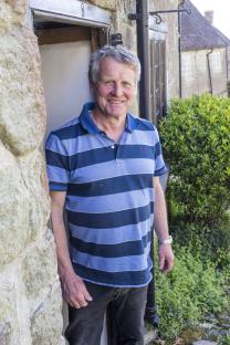 A man stands outside a stone cottage on Gold Hill in Shaftesbury.