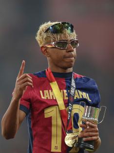Lamine Yamal of FC Barcelona celebrates a victory, holding a trophy and medal.