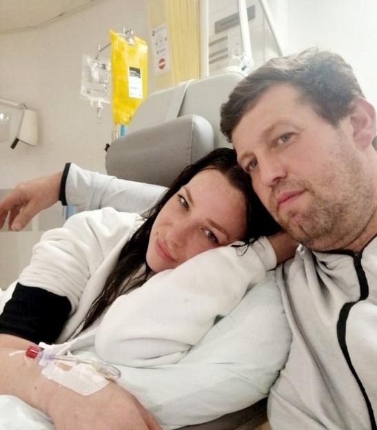 Chelsea Davies, 31, who has ovarian cancer, with her partner, Noel, 41, in a hospital bed.