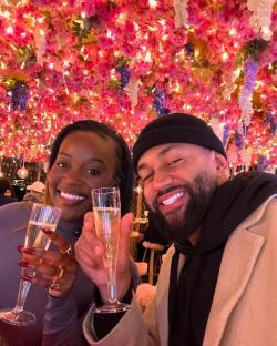 Couple toasting with champagne under a flower-covered ceiling.
