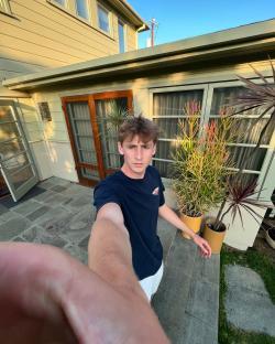 Selfie of a young man outside a house.