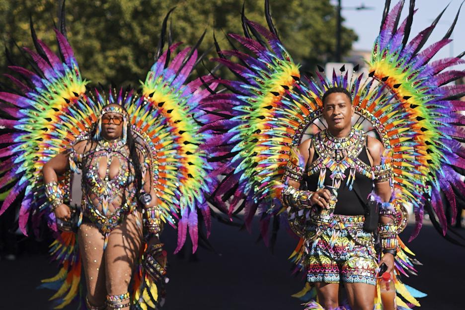 Two people in colorful feathered costumes at the Notting Hill Carnival.