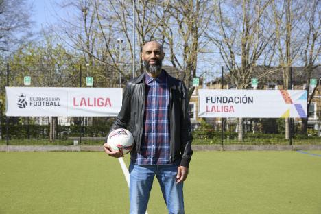 Frédéric Kanouté holding a soccer ball on a soccer field.