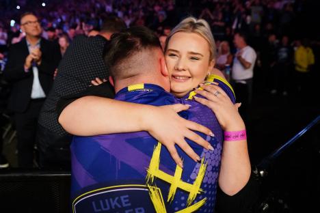 Luke Littler embracing his girlfriend after a darts victory.