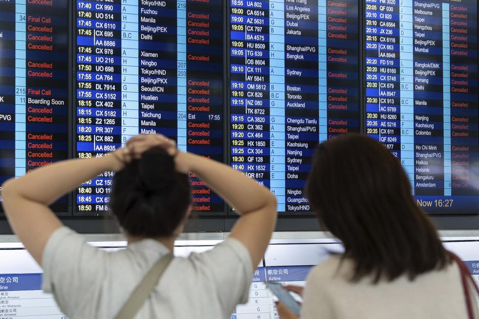 Passengers look at an information display board showing canceled flights due to the super typhoon Ragasa.