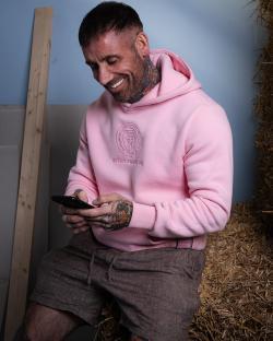 Man in pink Inter Miami CF hoodie using smartphone.