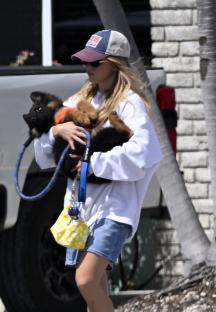 Sydney Sweeney carrying a German Shepherd puppy.